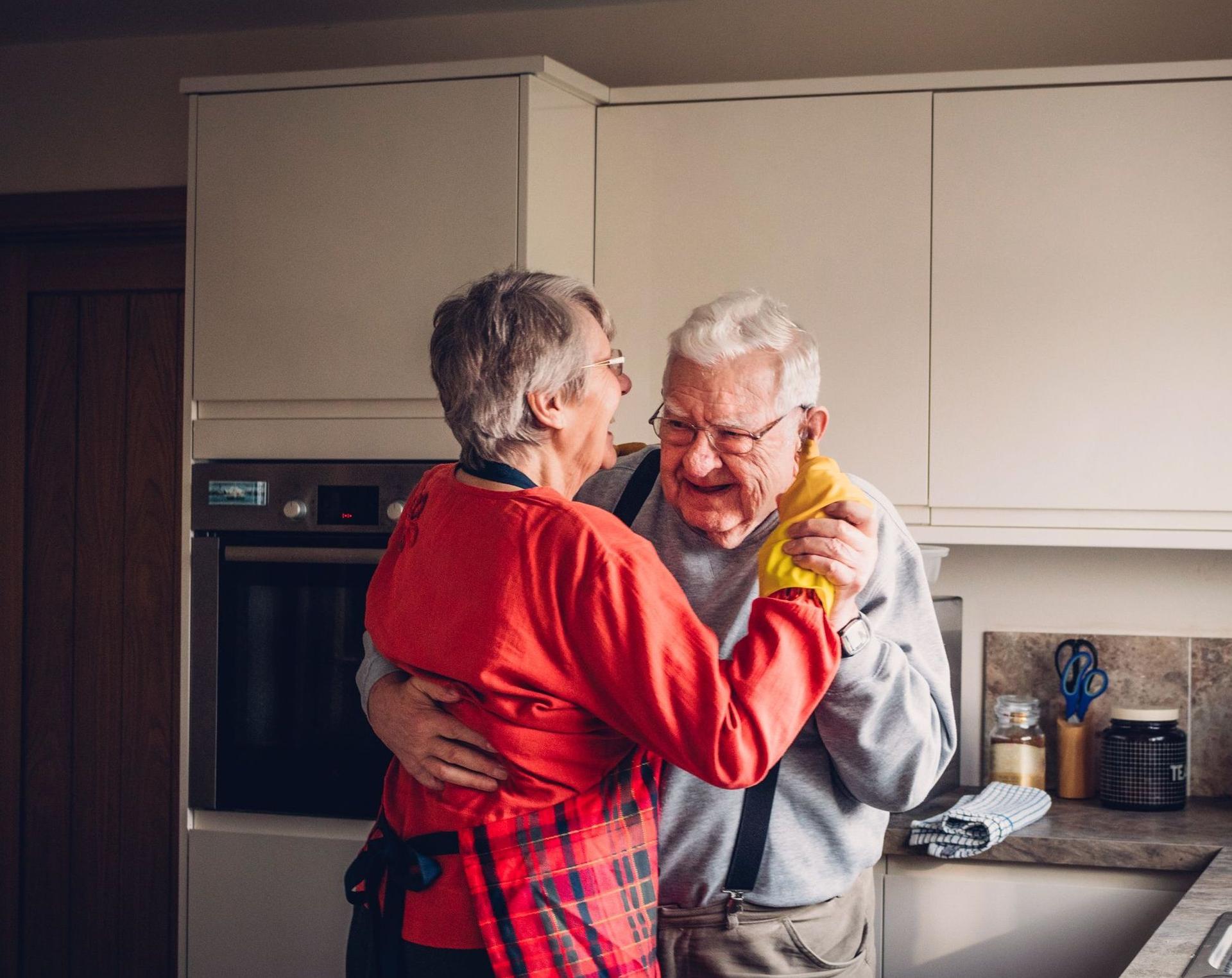 Ein älteres Paar tanzt in der Küche.