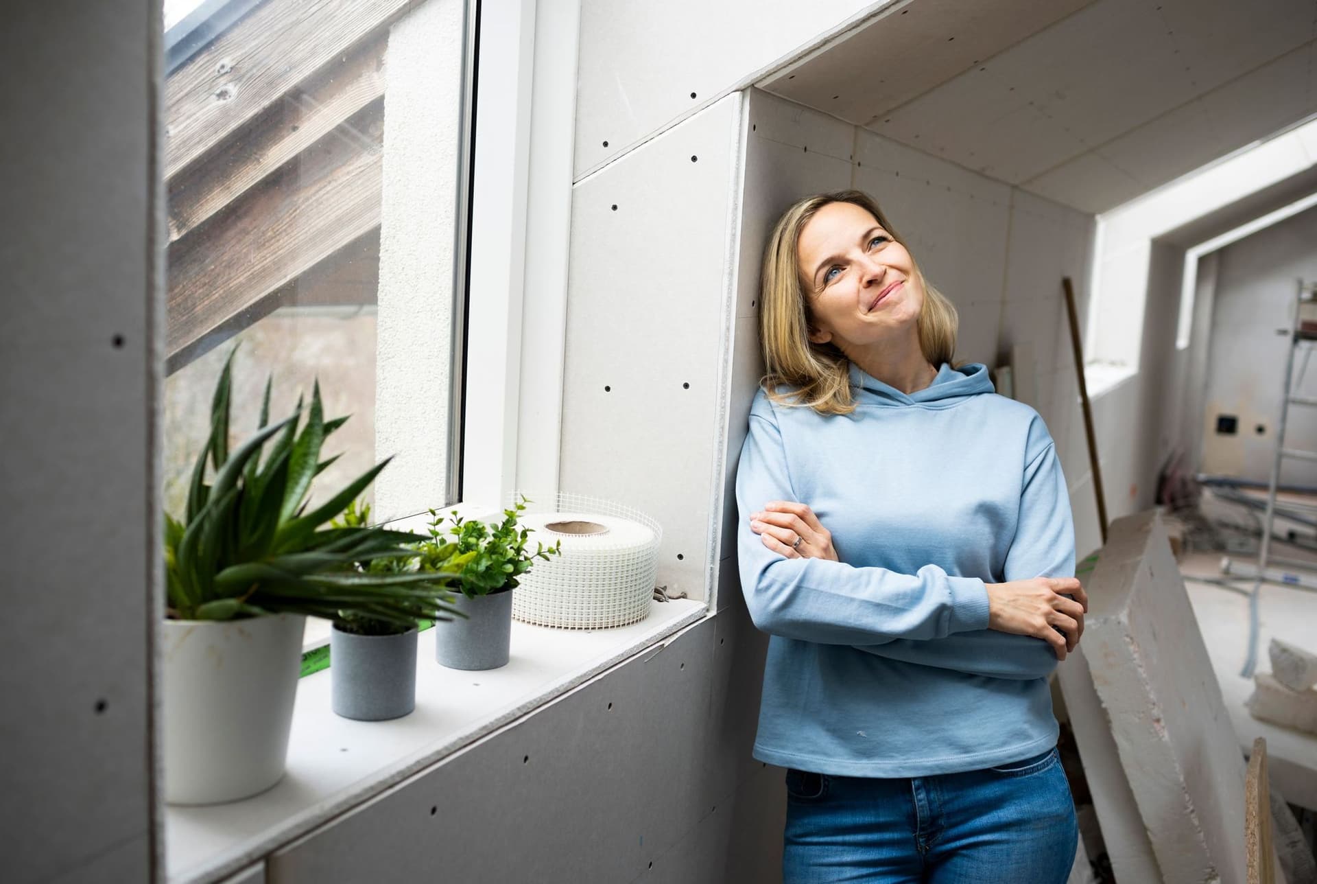 Eine Frau steht an angeleht an einer Wand und denkt über eine Vorfinanzierung nach.