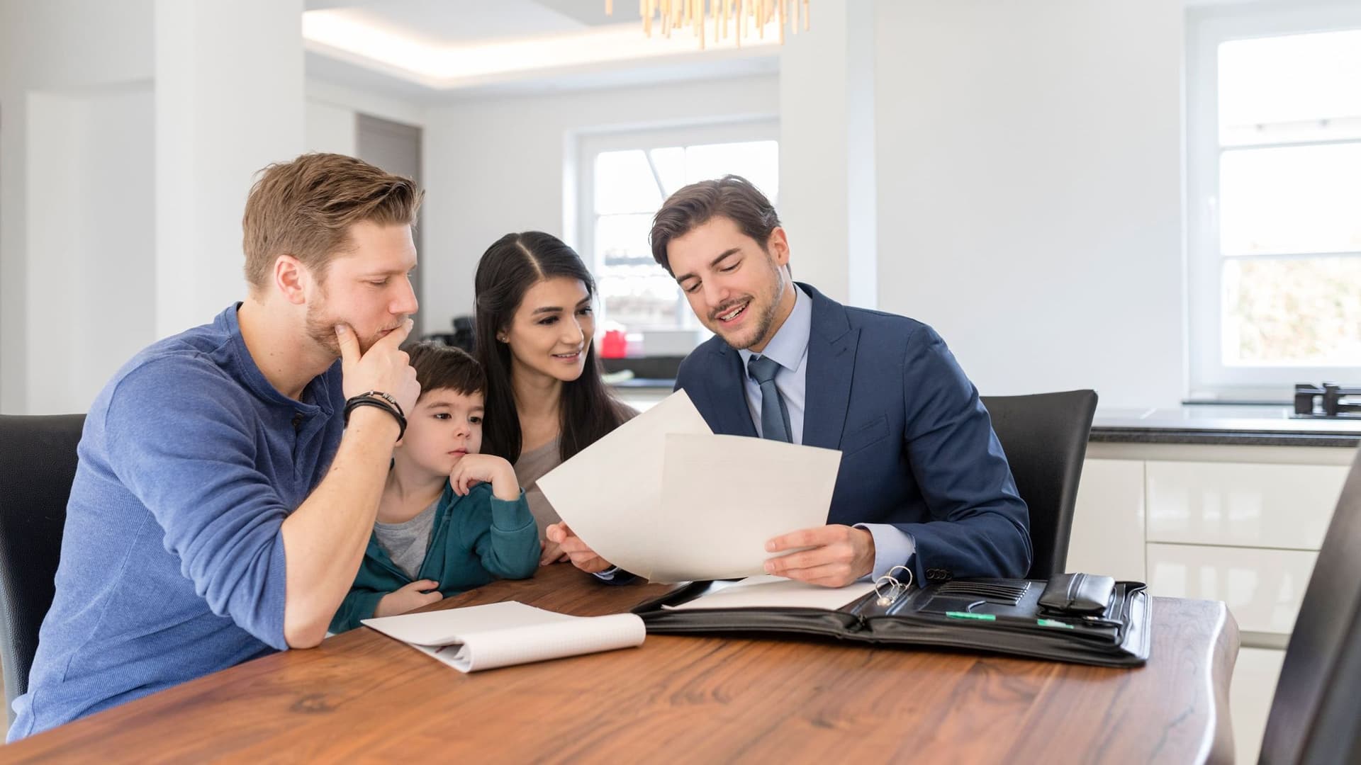 Familie sitzt am Schreibtisch mit Berater und bekommt eine Beratung zum Festdarlehen.