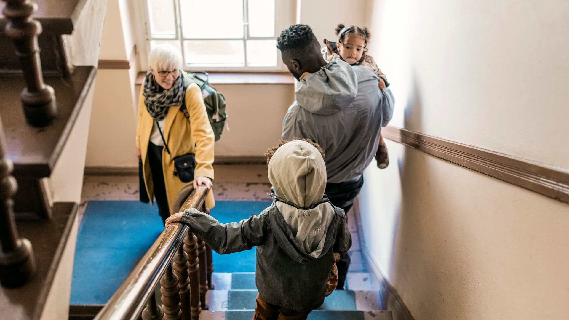 Eine Familie geht im Altbau die Treppe herunter.