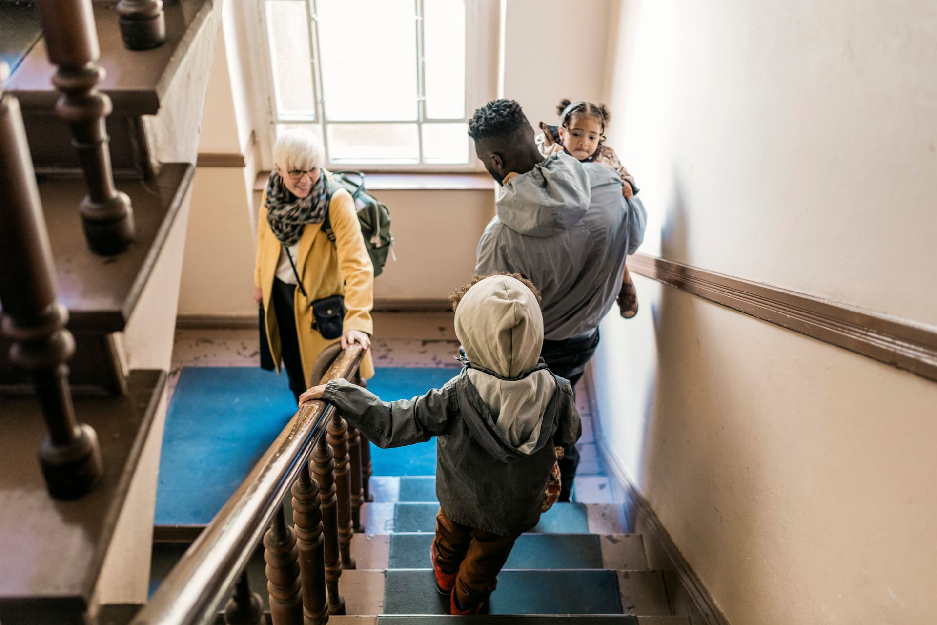 Eine Familie geht im Altbau die Treppe herunter.