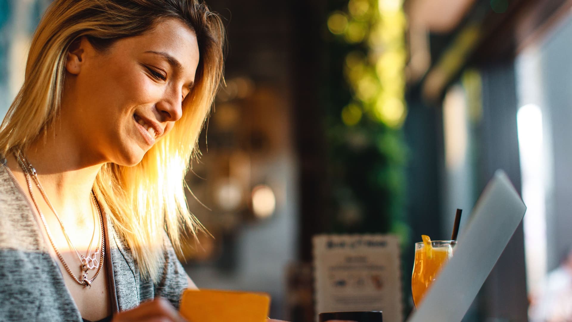 Frau in einen Cafe mit Laptop und Kreditkarte in der Hand.