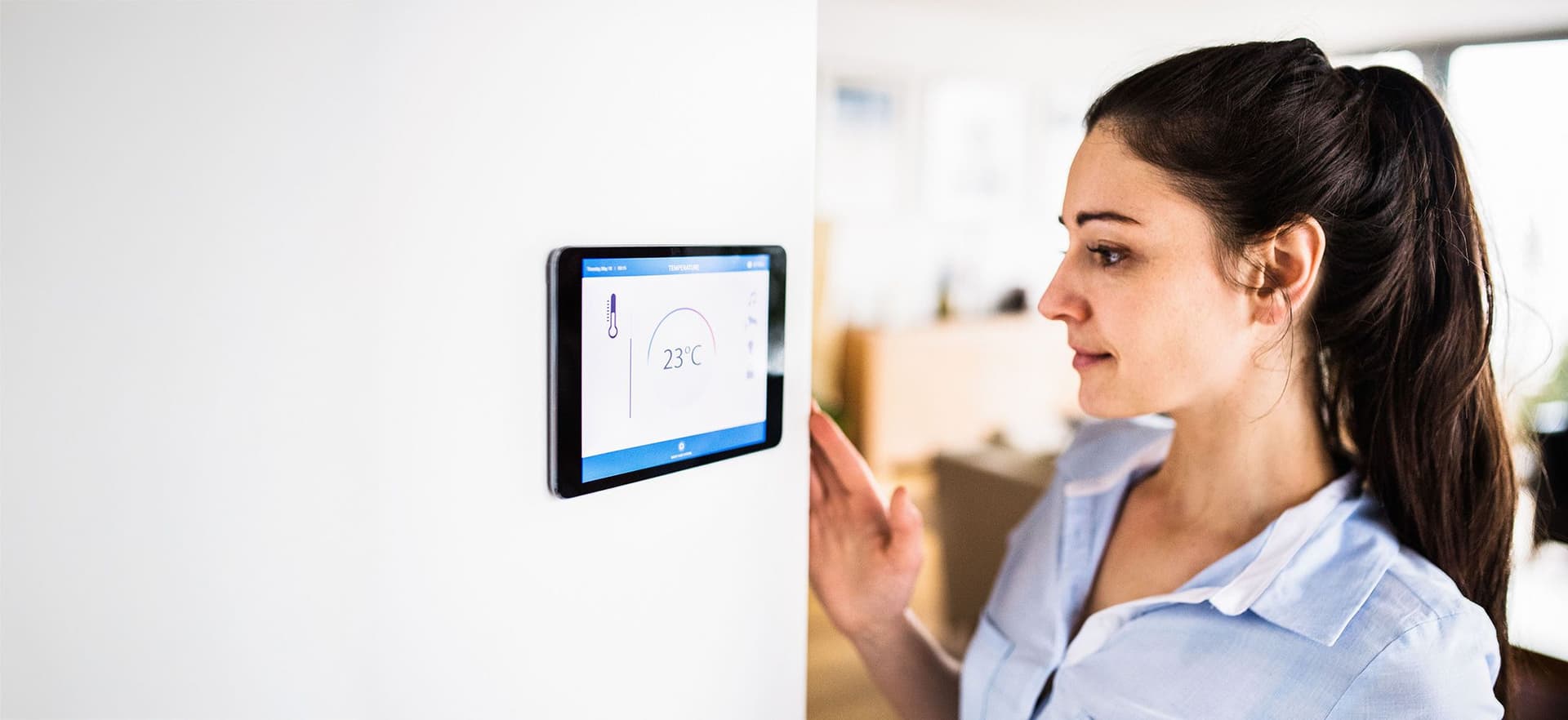 Frau guckt auf ein smartes Display an ihrer Hauswand
