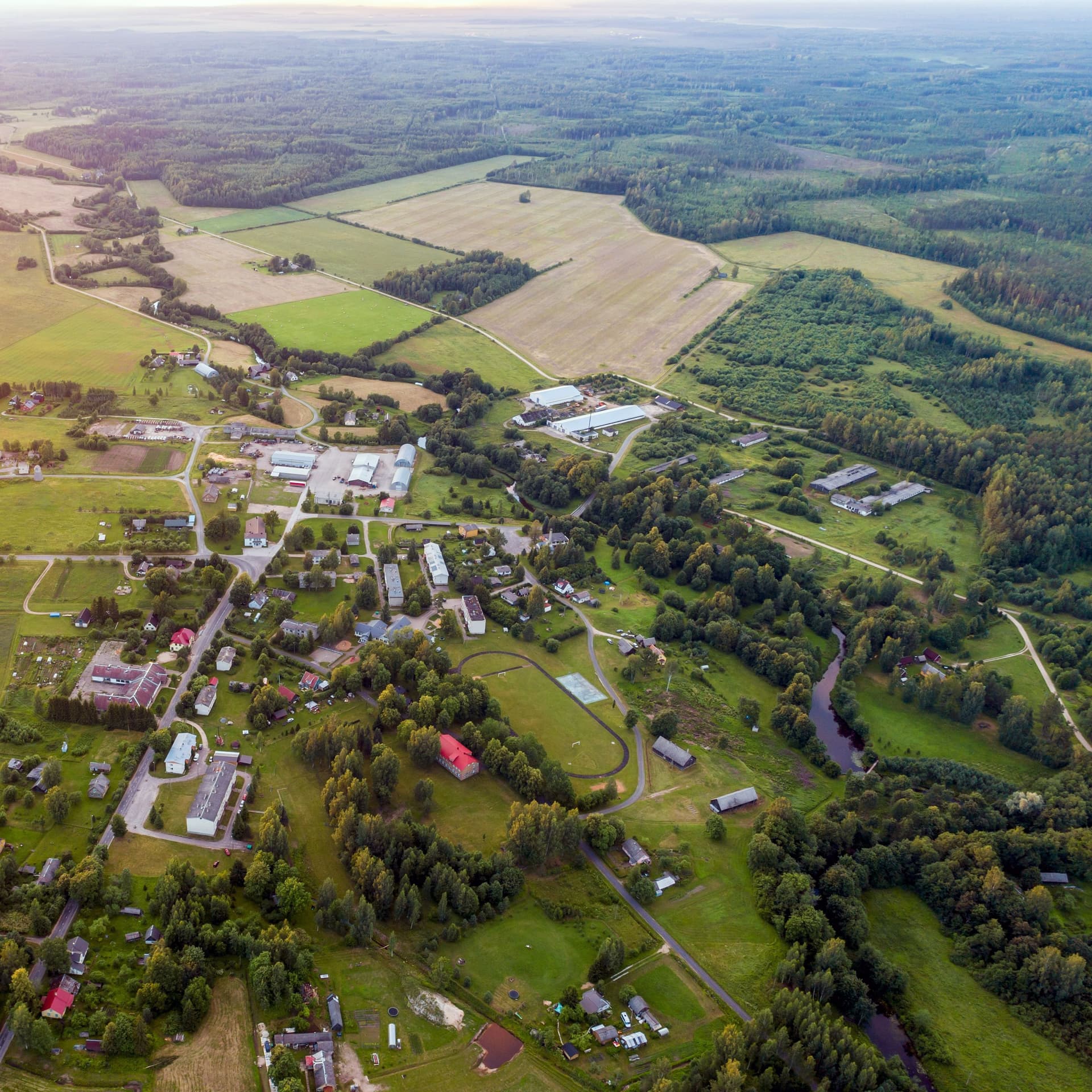 Luftaufnahme einer kleinen Ortschaft umgeben von Feldern und Wald.