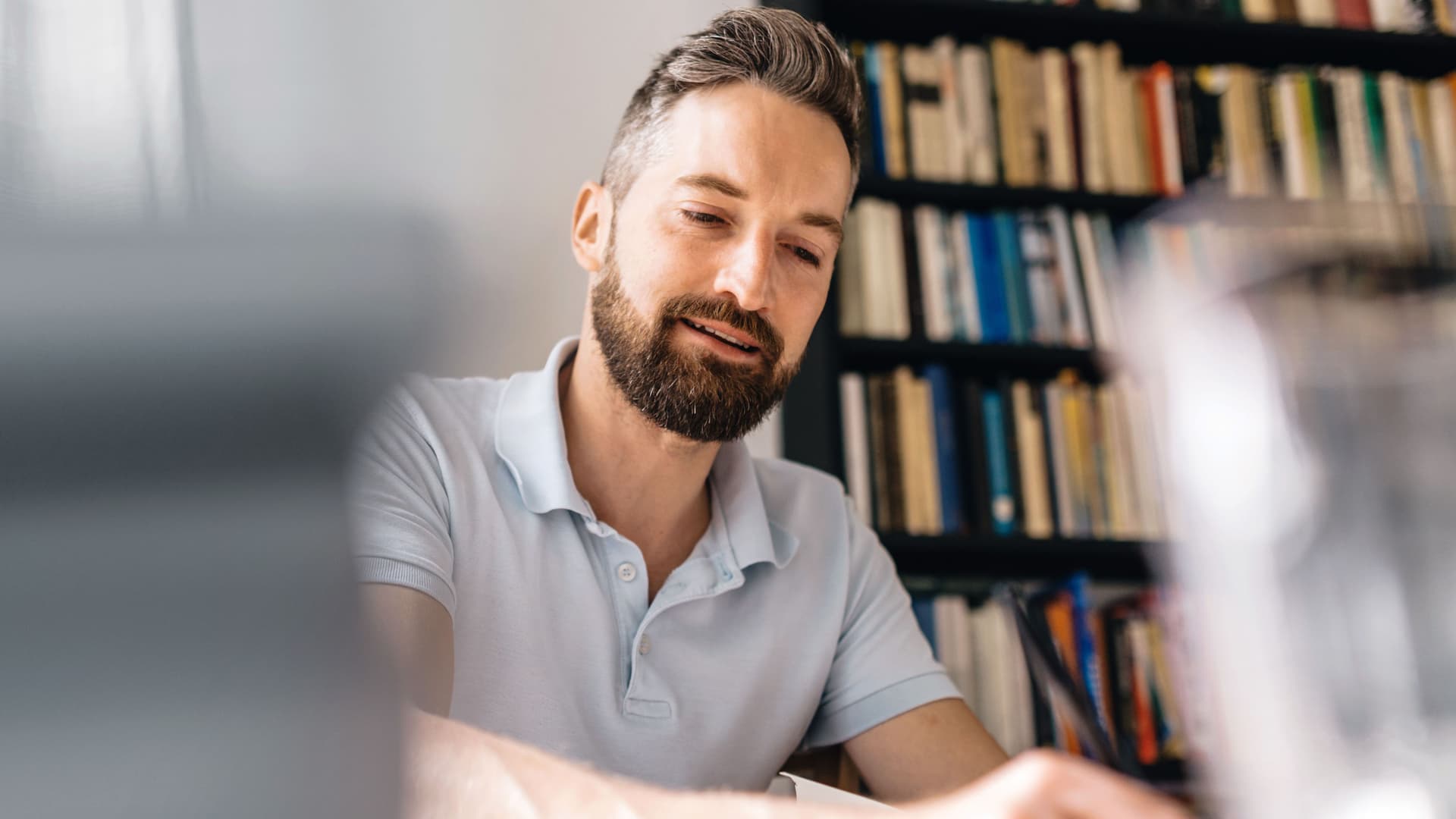 Mann sitzend am Tisch, der einen Stift in der Hand hält.