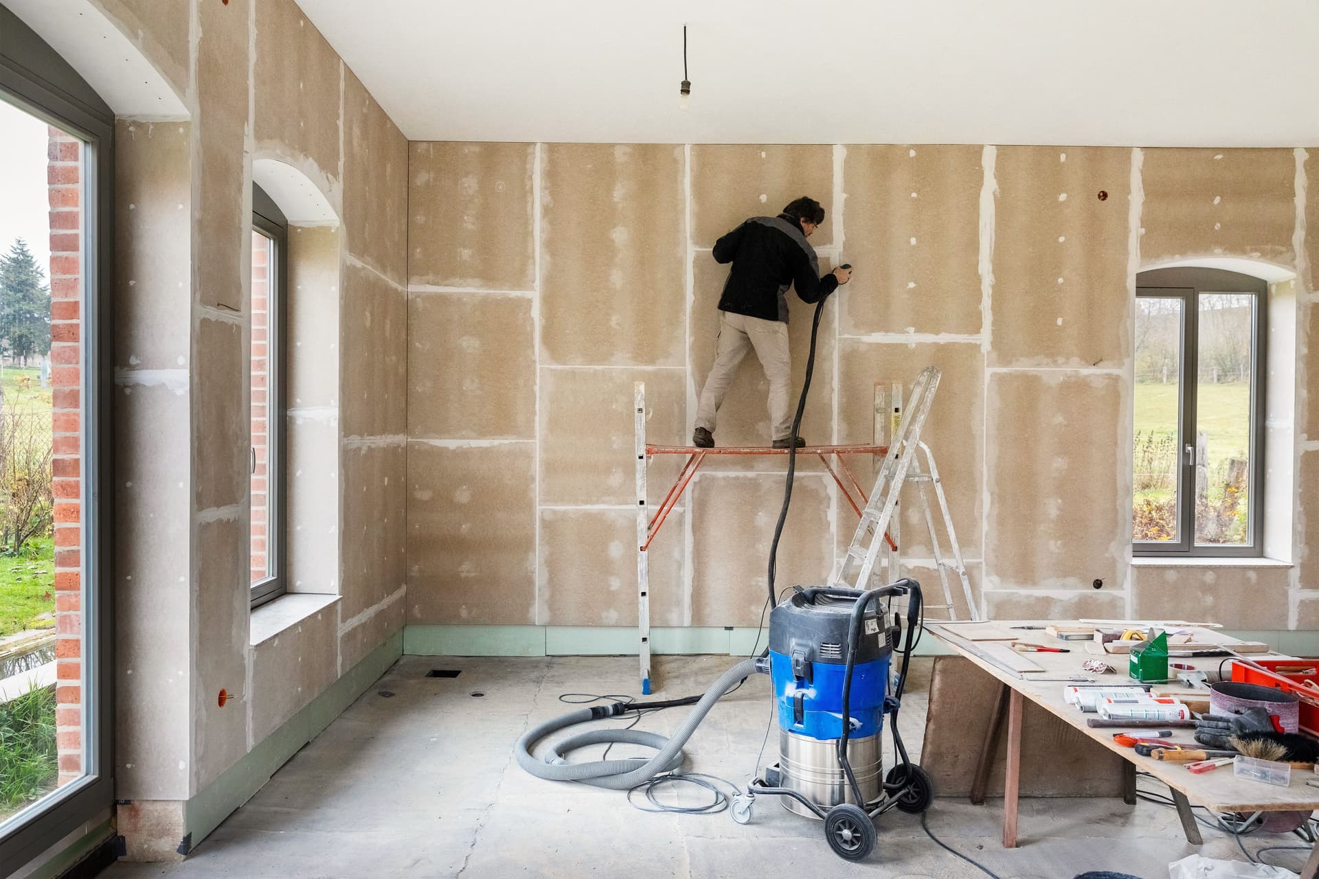 Schleifen der Fugen, Montage von Gipsfaserplatten vor einer Innendämmung mit Holzfaserplatten und OSB-Platten als Dampfbremse