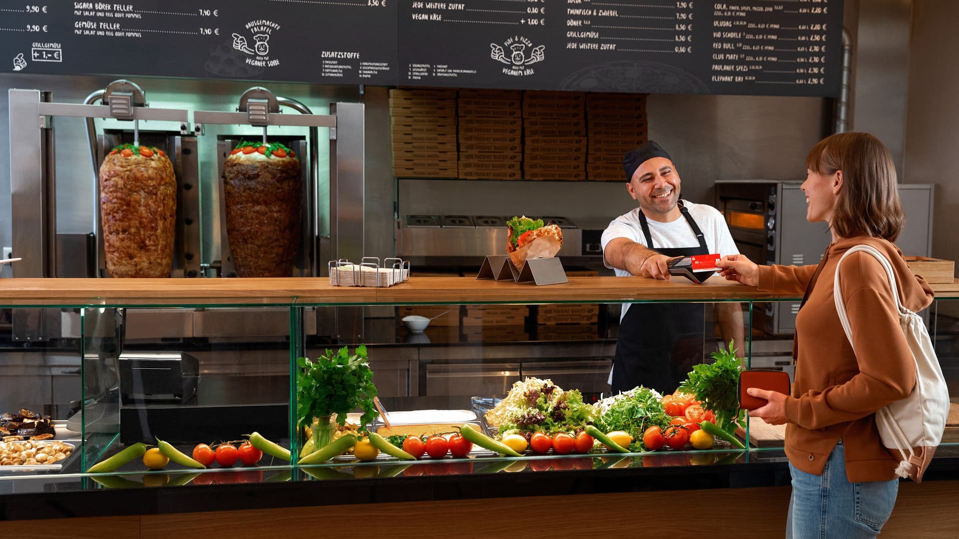 Frau bezahlt mit einer Sparkassen Karte in einem Döner Imbiss.