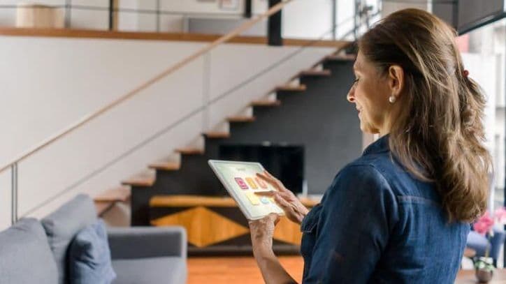 Eine Frau steuert auf einem Tablet die Beleuchtung ihres Eigenheimes