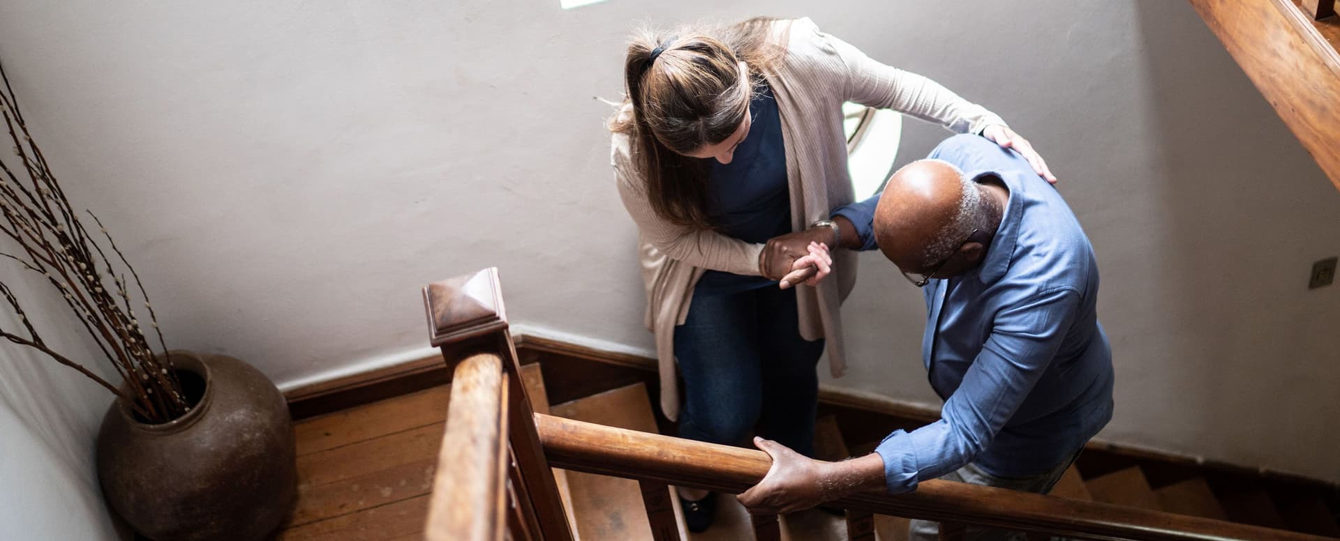 Älterer Mann wird von einer Frau beim Treppensteigen unterstützt