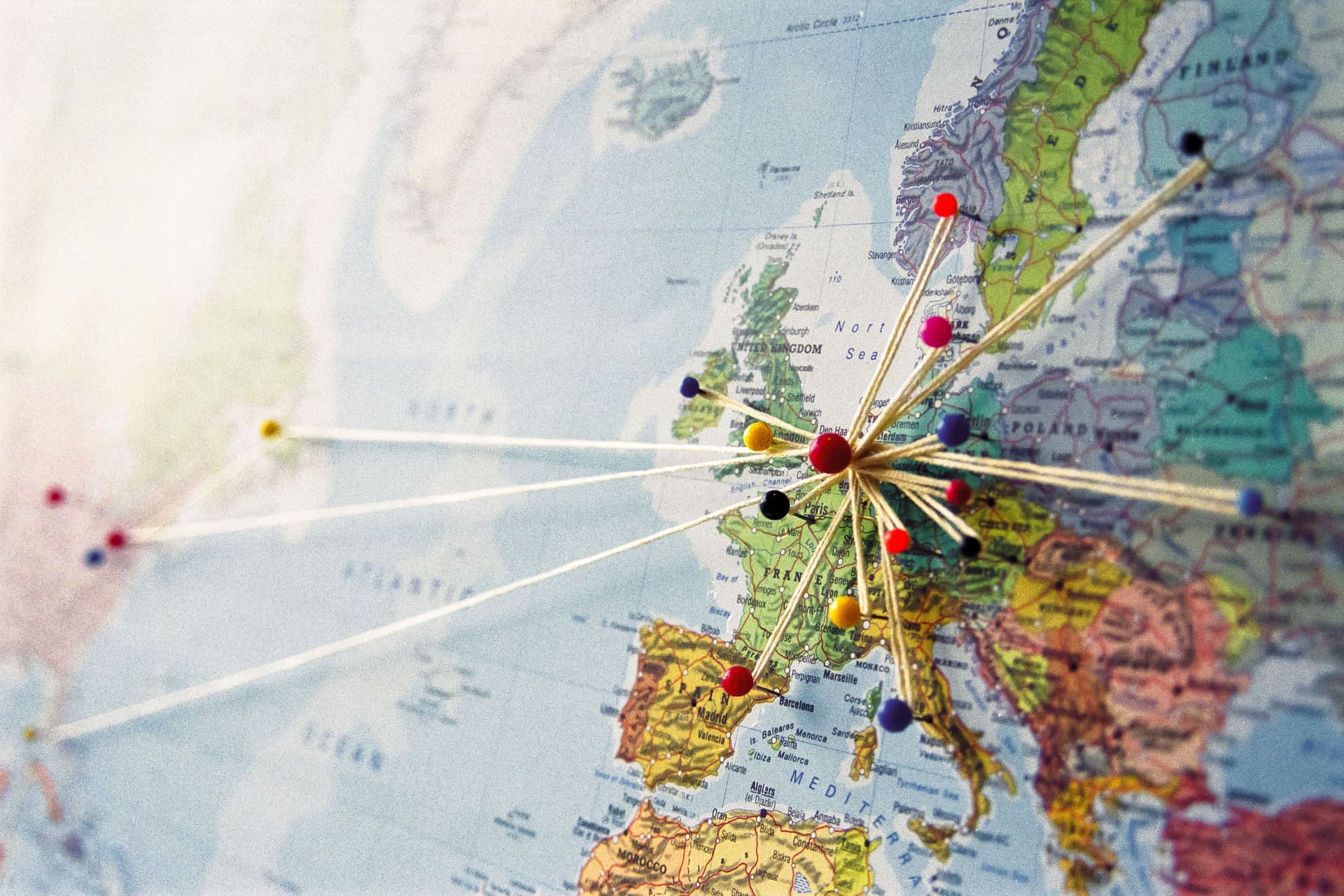 Karte von Europa und der Ostküste der U.S.A. mit Stecknadeln und Fäden versehen. Zentrum der Fäden ist Europa.