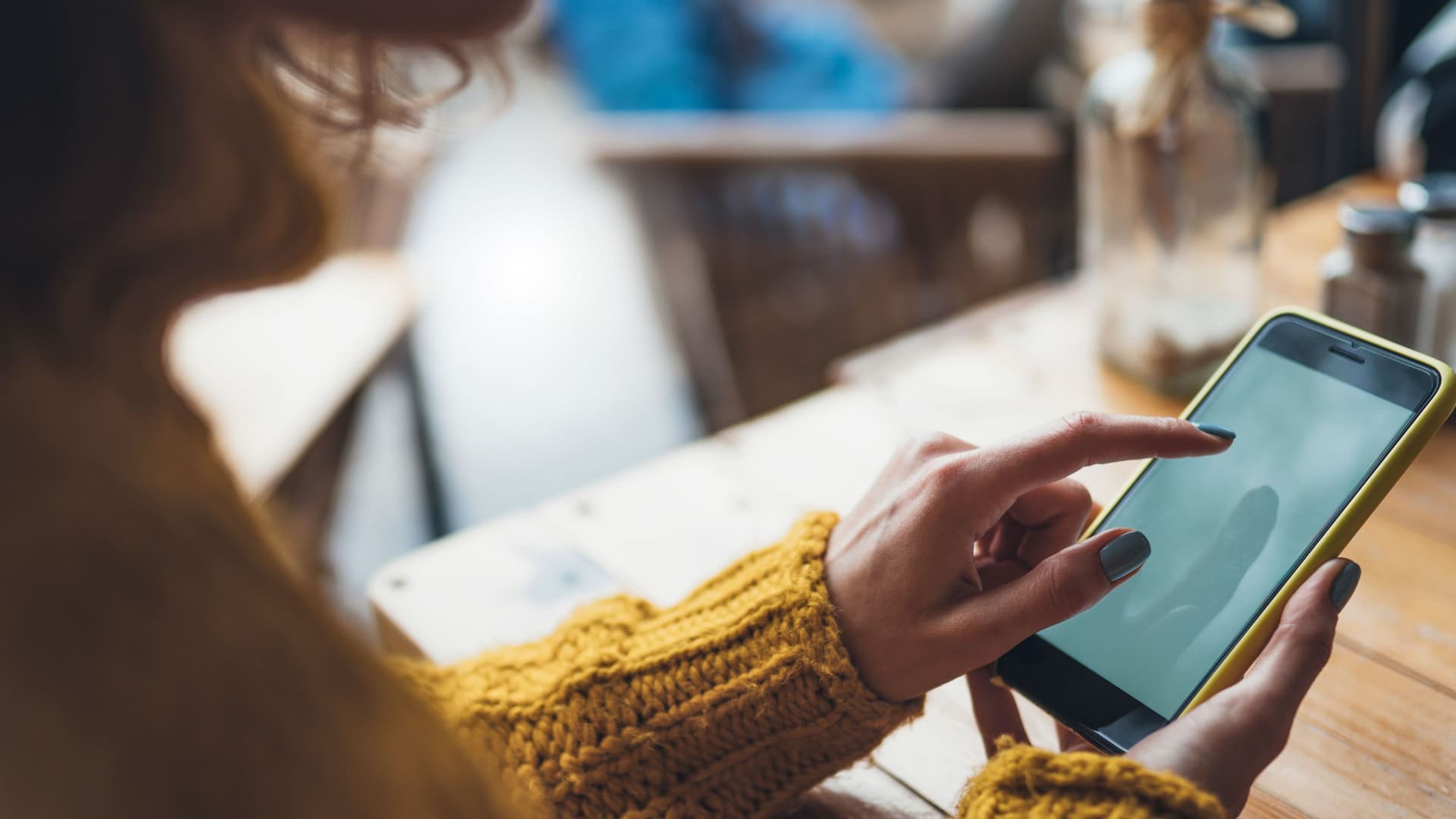 Eine Frau hält ein Smartphone in der Hand und tippt auf das Display.