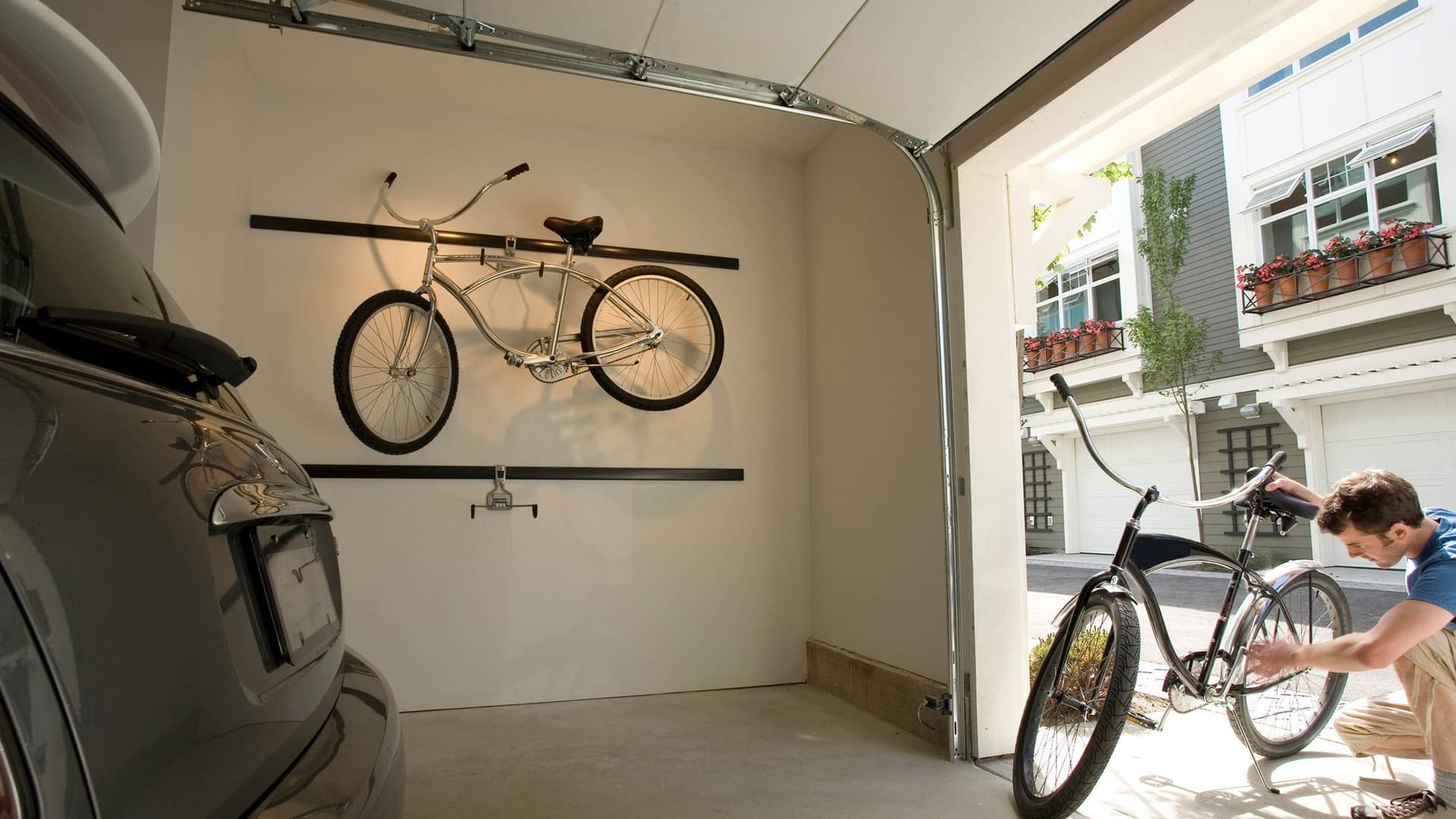 Ein Mann überprüft sorgfältig sein Fahrrad, während er in einem urbanen Umfeld steht. Er trägt sportliche Kleidung und scheint sich auf die Wartung oder Sicherheit des Fahrrads zu konzentrieren.
