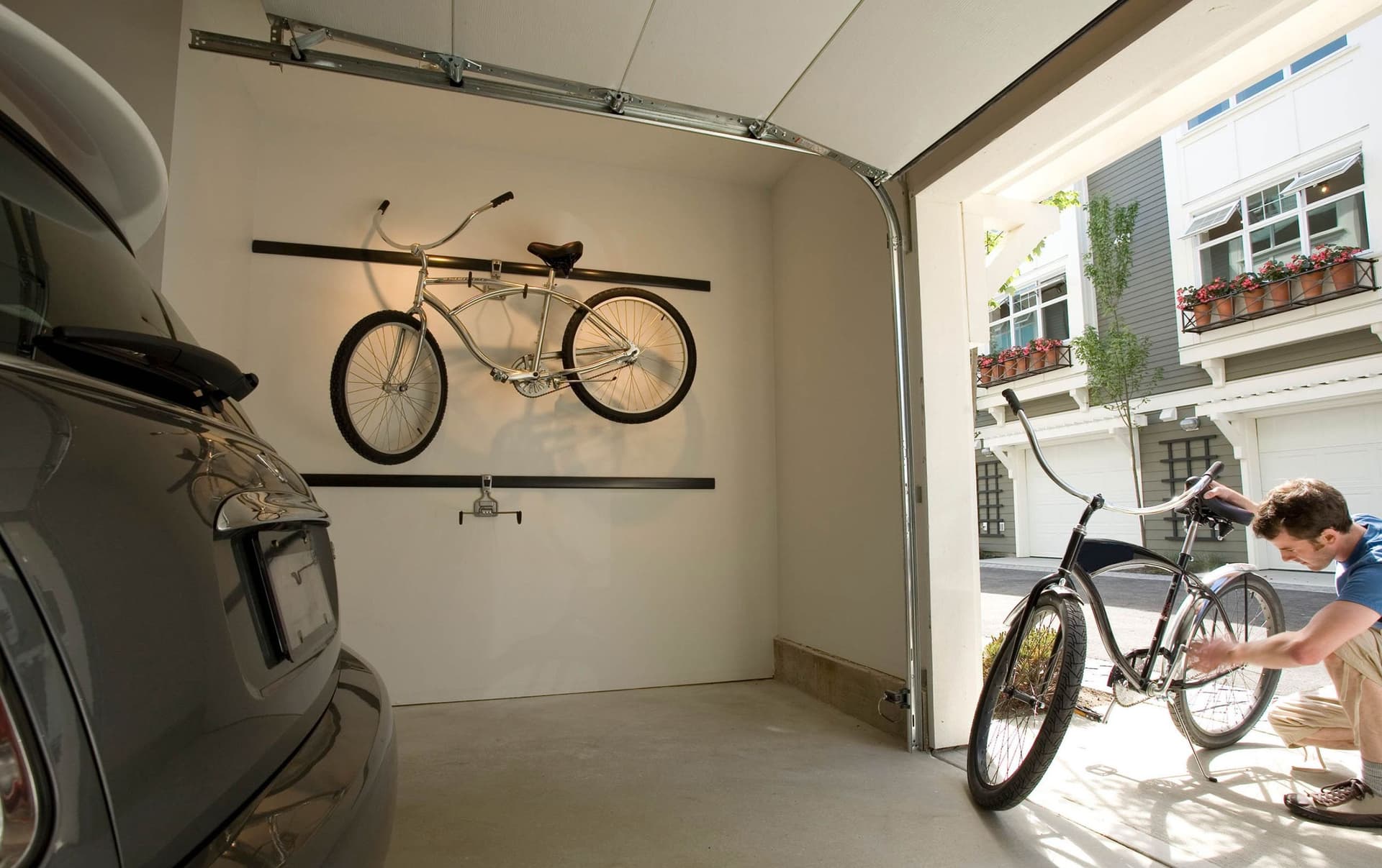 Ein Mann überprüft sorgfältig sein Fahrrad, während er in einem urbanen Umfeld steht. Er trägt sportliche Kleidung und scheint sich auf die Wartung oder Sicherheit des Fahrrads zu konzentrieren.
