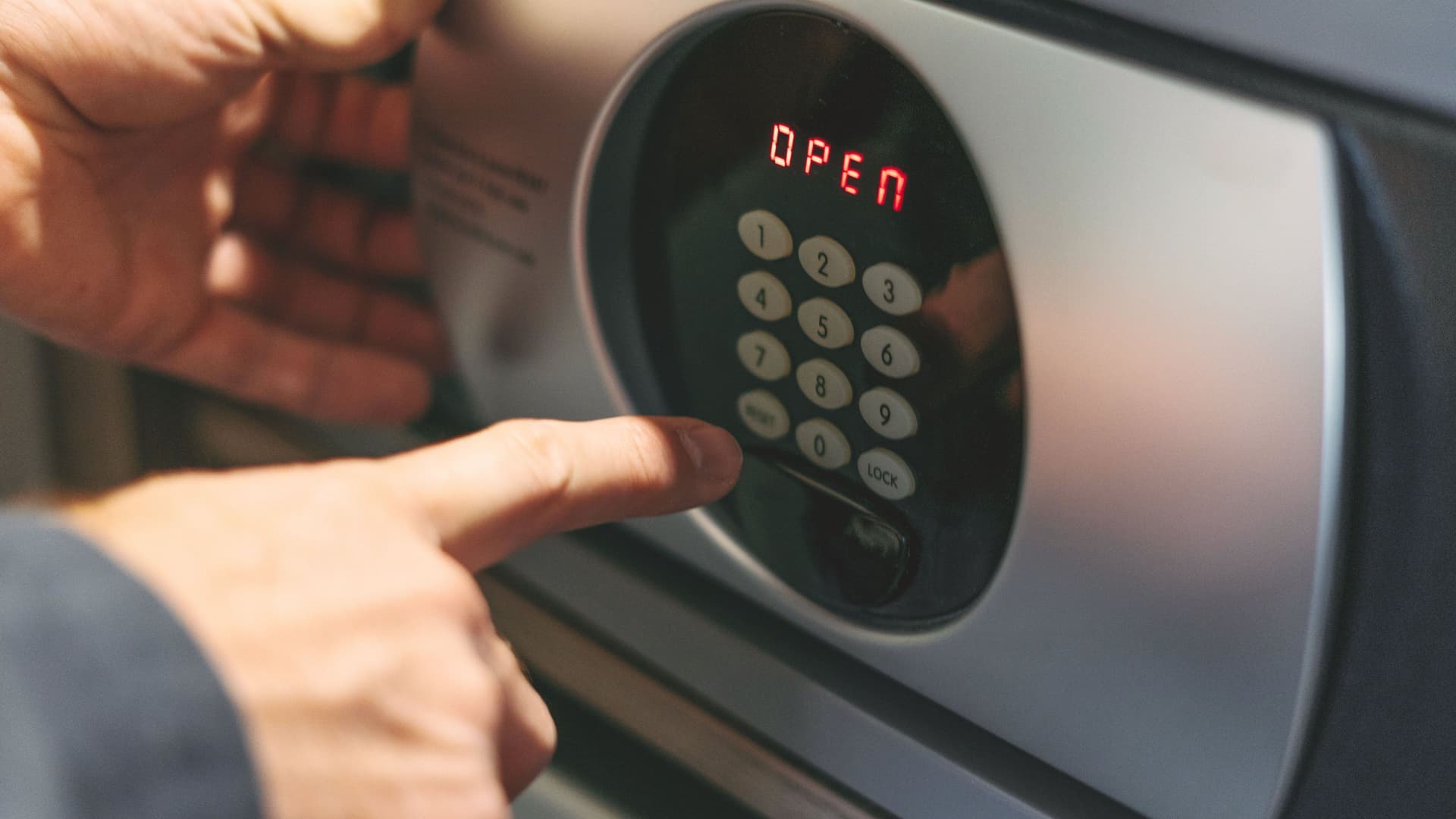 Männerhand öffnet einen Safe.