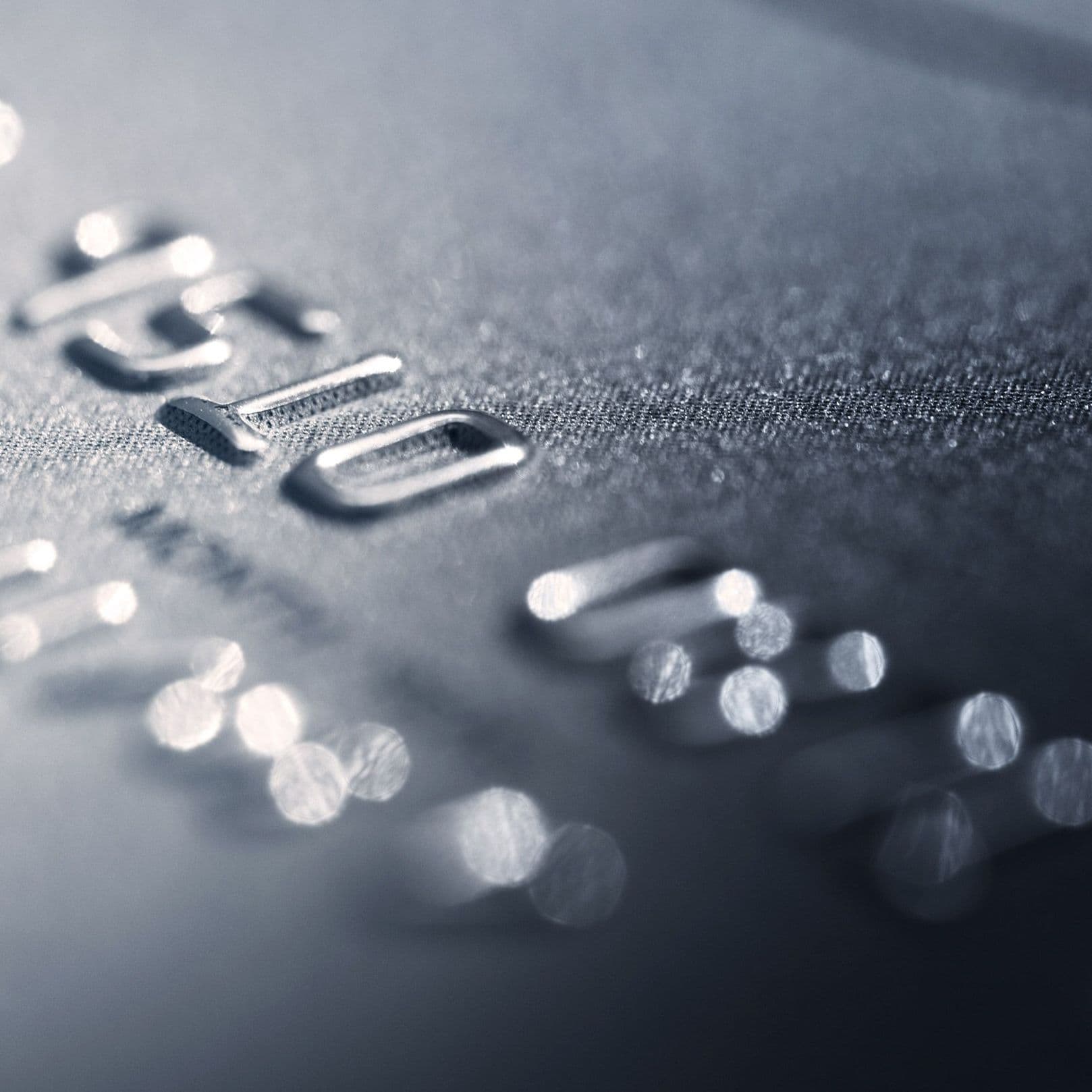 Nahaufnahme einer silbernen Kreditkarte auf der nur ein Ausschnitt der Nummer zu erkennen ist. Das Bild ist leicht seitlich aufgenommen worden und weißt eine hohe Unschärfe auf.