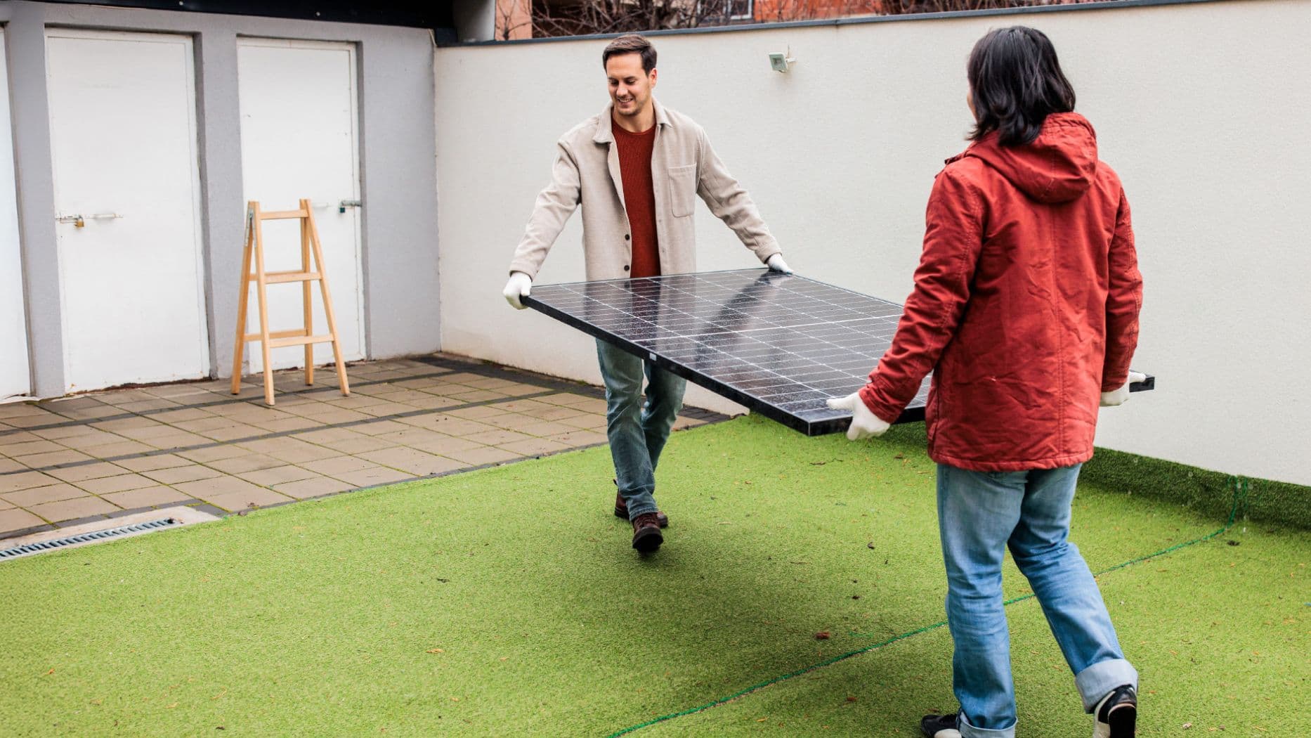 Zwei Personen tragen gemeinsam ein Solarmodul im Freien