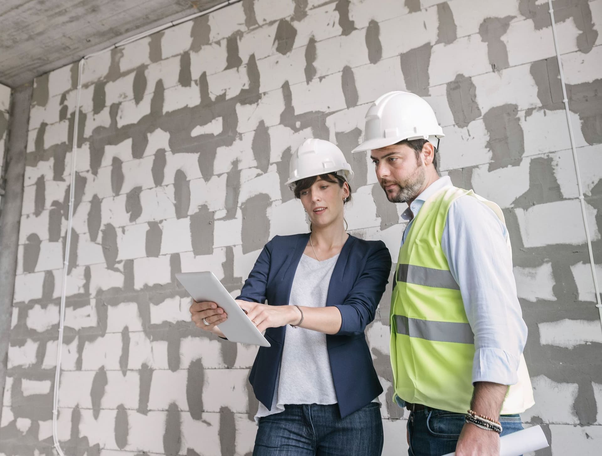 Zwei Architekten stehen auf einer Baustelle und benutzen ein Tablet